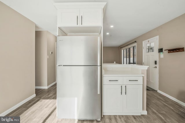 kitchen featuring stainless steel refrigerator, light hardwood / wood-style flooring, and white cabinets