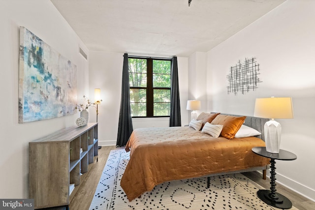 bedroom featuring baseboards, visible vents, and wood finished floors
