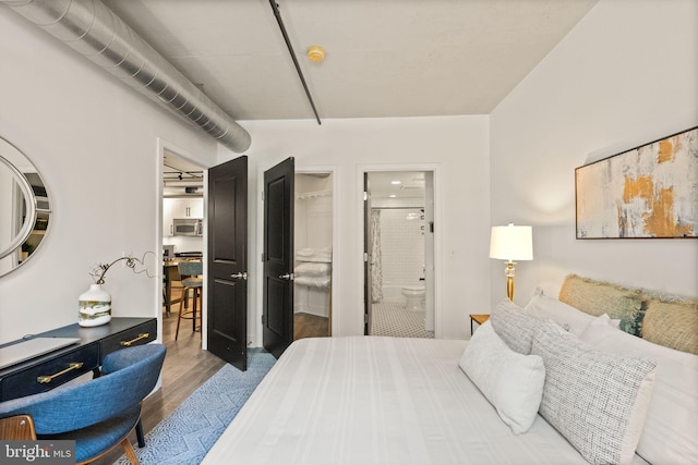 bedroom with a closet, connected bathroom, and wood finished floors