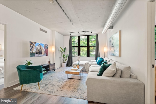 living room with baseboards, visible vents, track lighting, and wood finished floors