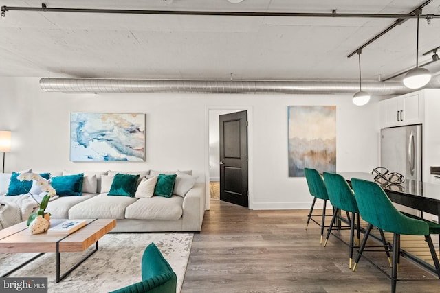 living area with baseboards and wood finished floors