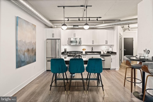 kitchen featuring light wood-style flooring, appliances with stainless steel finishes, dark countertops, and white cabinetry