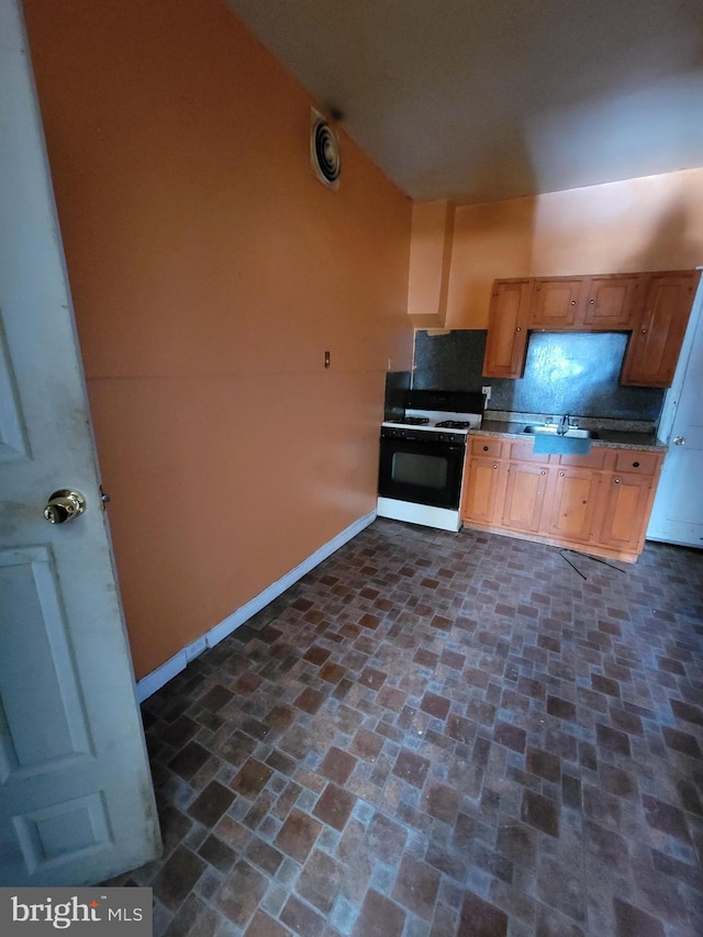 kitchen with decorative backsplash, sink, and white range with gas stovetop