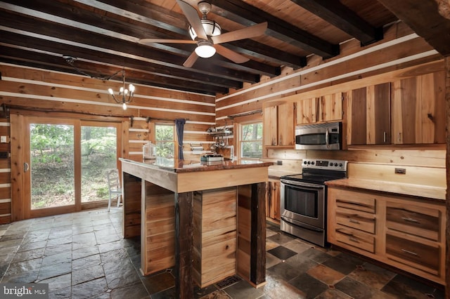 kitchen featuring appliances with stainless steel finishes, stone tile flooring, beamed ceiling, ceiling fan, and a kitchen island