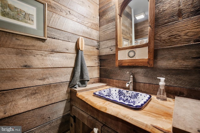 bathroom featuring a sink and wood walls