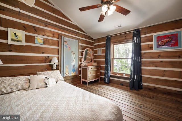 bedroom with vaulted ceiling, wood walls, and wood-type flooring