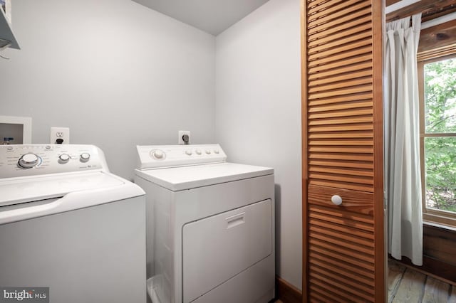 clothes washing area featuring separate washer and dryer and wood finished floors