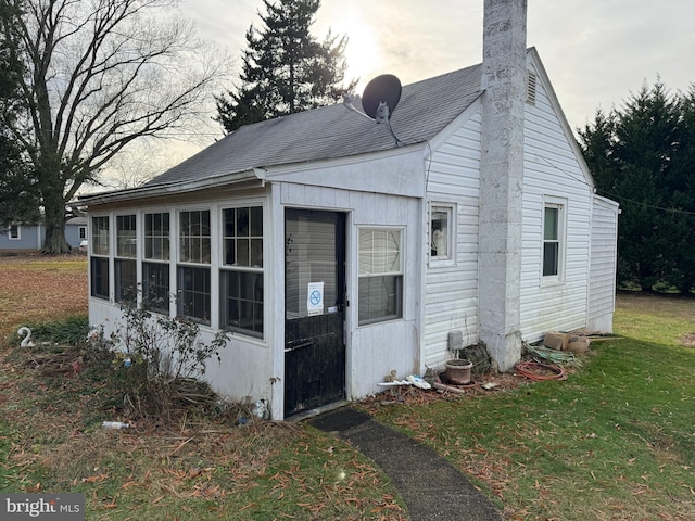 view of property exterior with a lawn and a sunroom