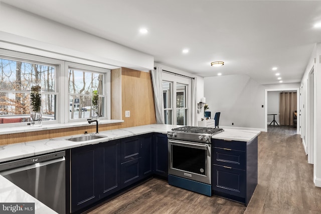 kitchen with light stone counters, kitchen peninsula, dark hardwood / wood-style floors, appliances with stainless steel finishes, and sink