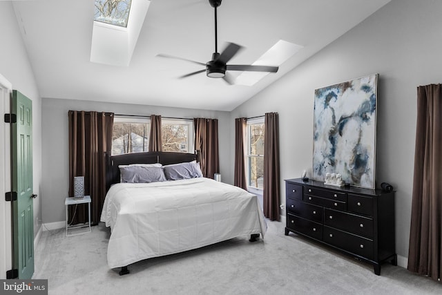 bedroom featuring ceiling fan, vaulted ceiling with skylight, and light carpet