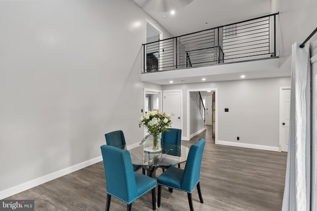 dining space featuring a towering ceiling and dark hardwood / wood-style floors