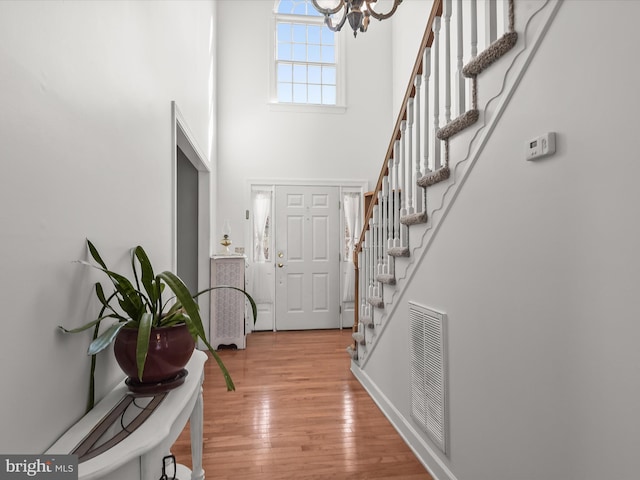 foyer entrance with a high ceiling, a chandelier, and light hardwood / wood-style flooring