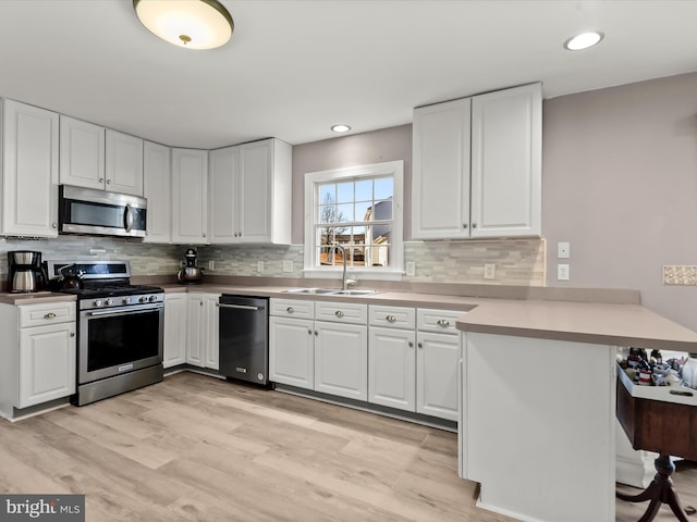 kitchen with white cabinetry, sink, kitchen peninsula, and appliances with stainless steel finishes