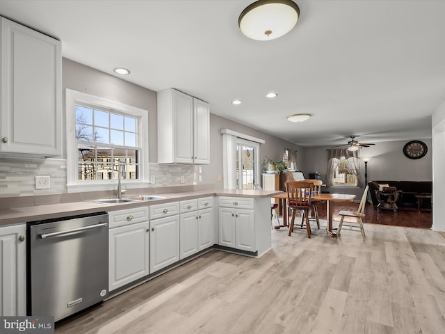 kitchen with sink, dishwasher, white cabinetry, light hardwood / wood-style floors, and kitchen peninsula