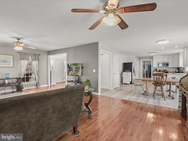 living room with light hardwood / wood-style floors and ceiling fan