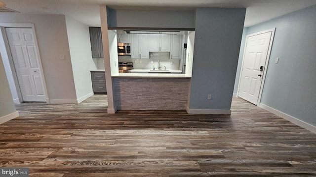 interior space featuring sink, dark hardwood / wood-style flooring, stainless steel appliances, and tasteful backsplash