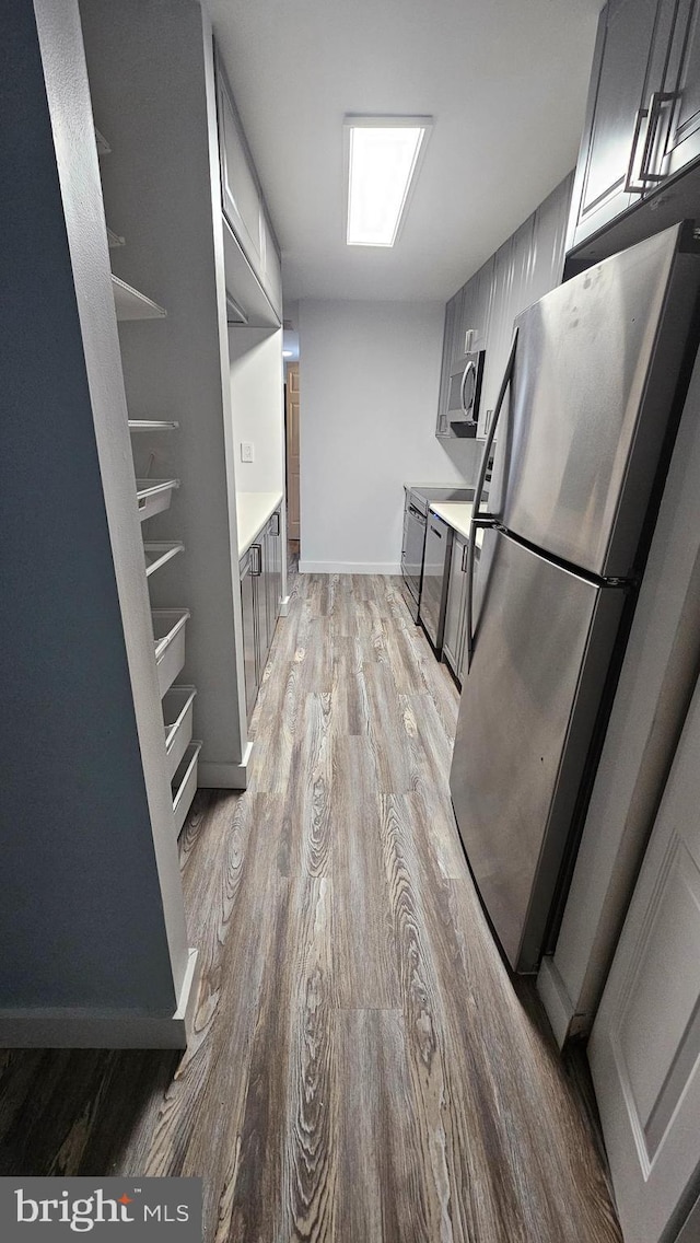 kitchen featuring gray cabinets, light hardwood / wood-style flooring, and stainless steel appliances