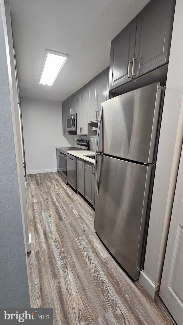 kitchen with gray cabinetry, light hardwood / wood-style floors, and stainless steel appliances