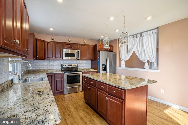 kitchen with a center island, light hardwood / wood-style flooring, appliances with stainless steel finishes, decorative light fixtures, and light stone counters