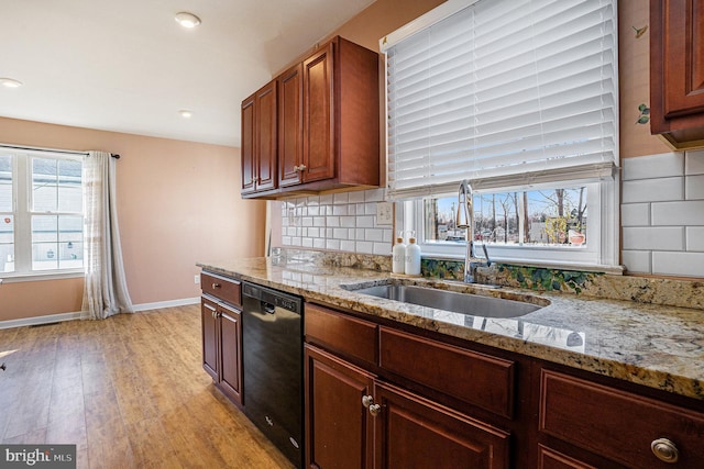 kitchen with decorative backsplash, light stone countertops, light wood-type flooring, sink, and dishwasher