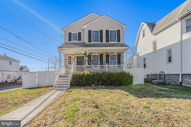 view of property featuring covered porch and a front yard