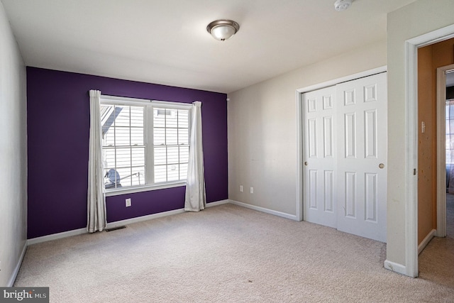 unfurnished bedroom with a closet and light colored carpet