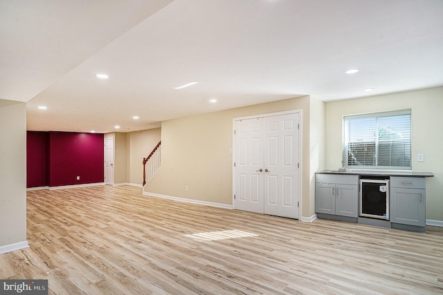 basement with light wood-type flooring and wine cooler