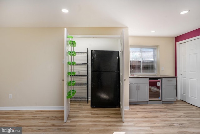 kitchen with light wood-type flooring, black fridge, sink, gray cabinets, and wine cooler