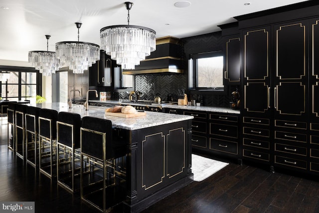 kitchen featuring a kitchen island with sink, dark hardwood / wood-style flooring, hanging light fixtures, and a notable chandelier