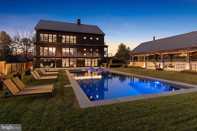 pool at dusk with a lawn, a patio area, and a gazebo