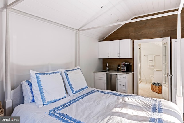 bedroom with lofted ceiling, wooden walls, ensuite bath, indoor wet bar, and stainless steel refrigerator