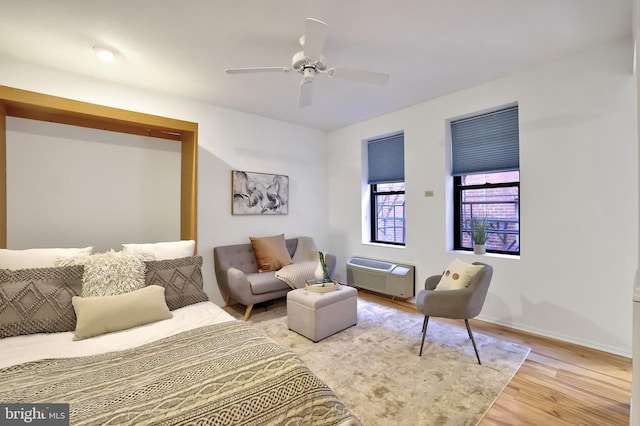 bedroom featuring hardwood / wood-style floors, ceiling fan, and an AC wall unit