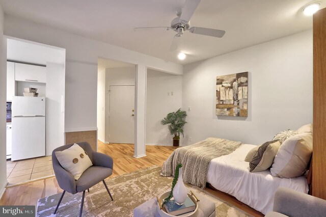 bedroom with ceiling fan, white fridge, and light hardwood / wood-style flooring