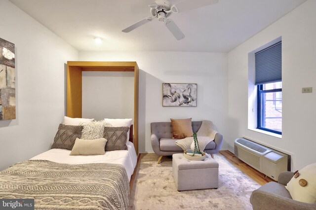 bedroom with an AC wall unit, ceiling fan, and light hardwood / wood-style floors