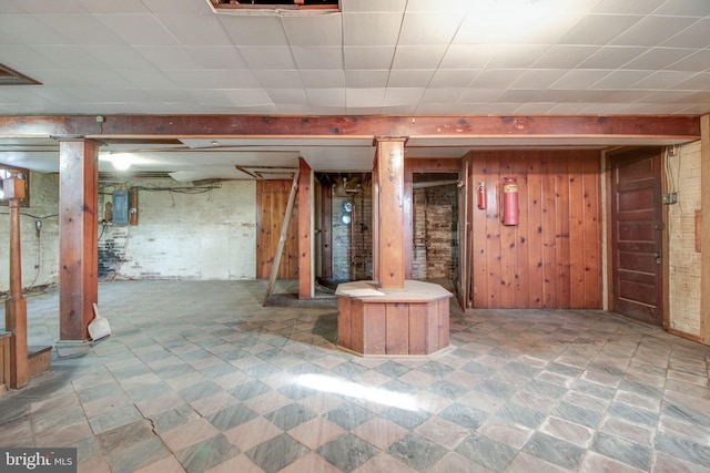 basement featuring electric panel and wooden walls