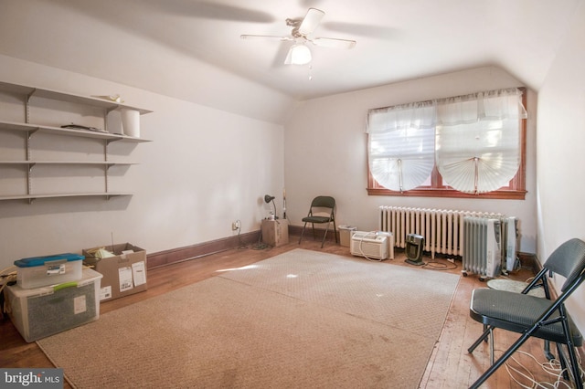 interior space with radiator, ceiling fan, wood-type flooring, and vaulted ceiling