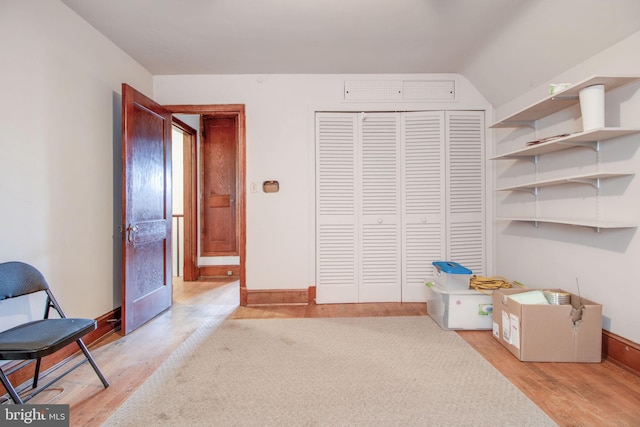 interior space featuring light wood-type flooring, vaulted ceiling, and a closet