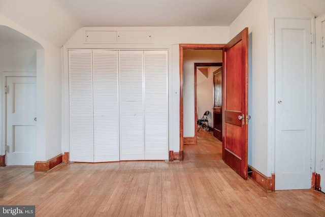 unfurnished bedroom with light hardwood / wood-style floors, a closet, and lofted ceiling