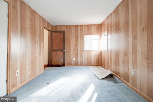 unfurnished room with wooden walls and light colored carpet