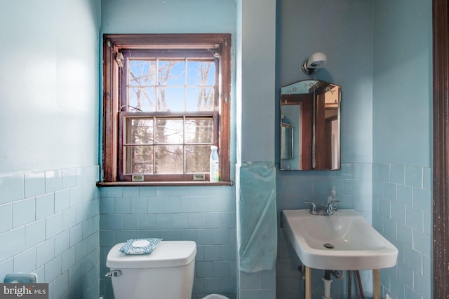 bathroom featuring toilet, tile walls, and sink