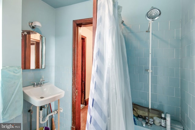 bathroom featuring a shower with curtain, sink, hardwood / wood-style floors, and tile walls