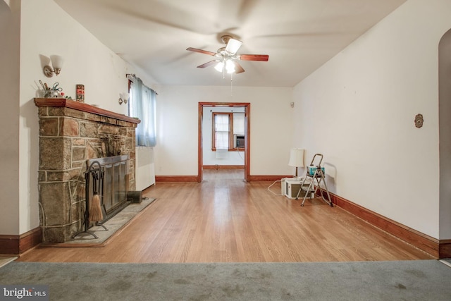 living area featuring a fireplace, wood-type flooring, and ceiling fan