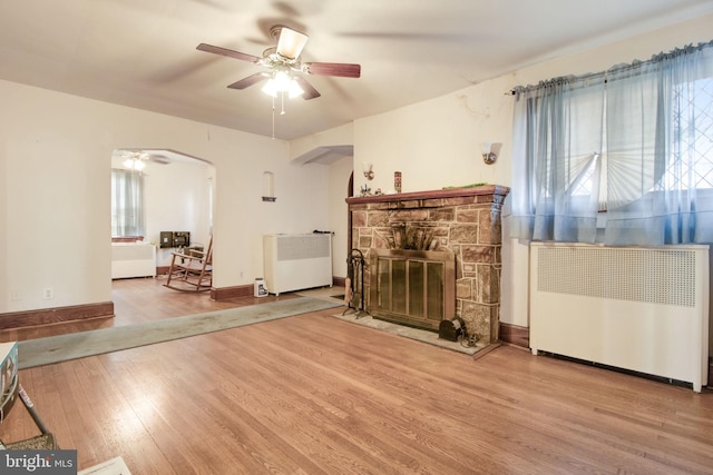 living room with ceiling fan, a healthy amount of sunlight, light hardwood / wood-style floors, and radiator