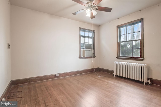 empty room featuring ceiling fan, radiator heating unit, hardwood / wood-style floors, and plenty of natural light