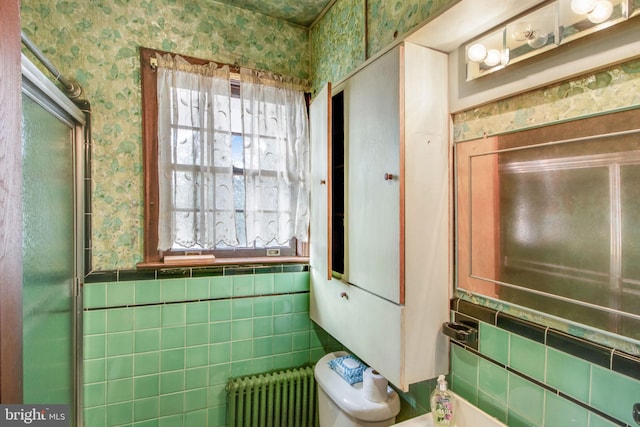 bathroom with radiator, tile walls, and toilet