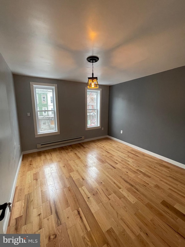 unfurnished dining area featuring light hardwood / wood-style flooring, baseboard heating, and a healthy amount of sunlight