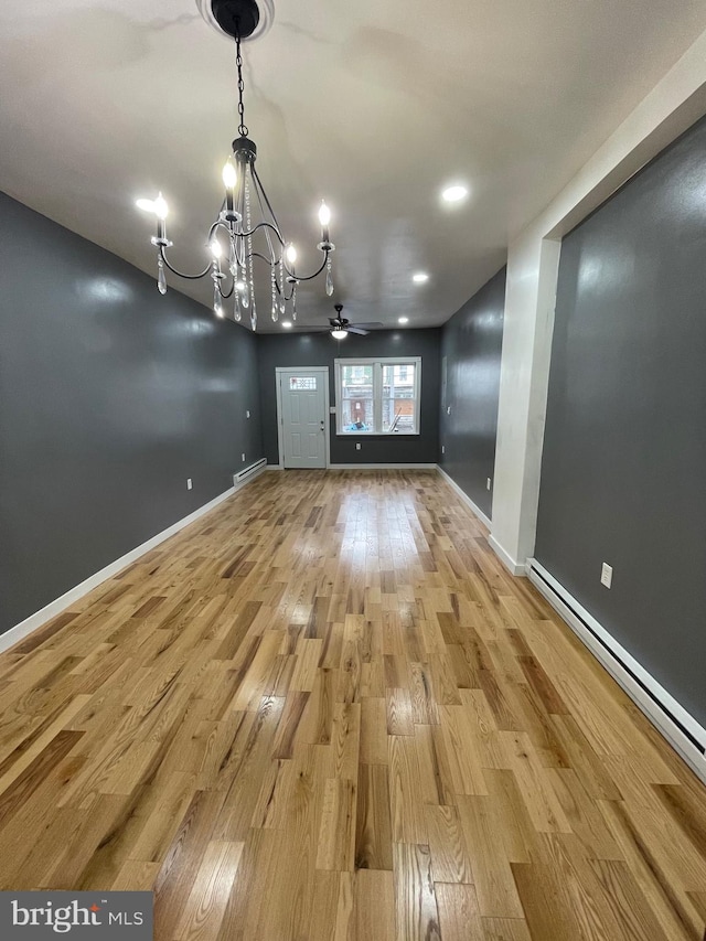 unfurnished dining area featuring ceiling fan with notable chandelier, a baseboard radiator, and light hardwood / wood-style flooring