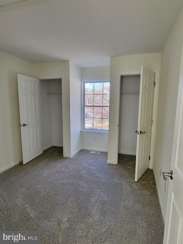 unfurnished bedroom featuring carpet flooring and multiple closets