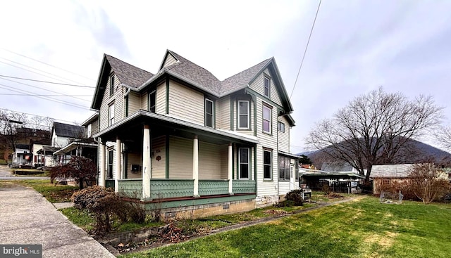 view of side of home featuring covered porch and a yard