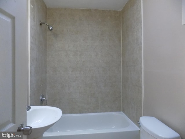 bathroom with toilet and tiled shower / bath